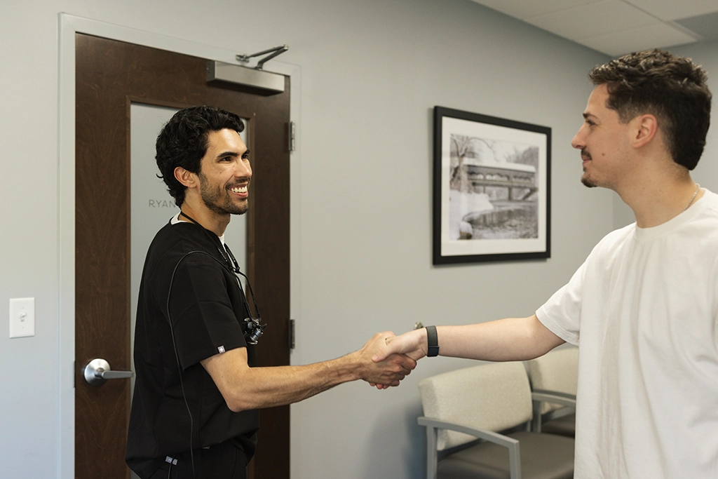 Dental office staff warmly greeting a patient at the reception desk